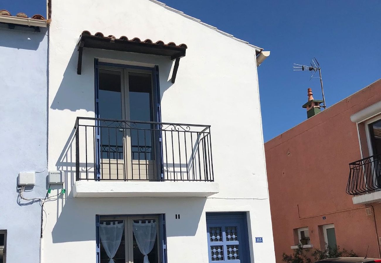 Front of the house . the house is white and has  blue windows and door